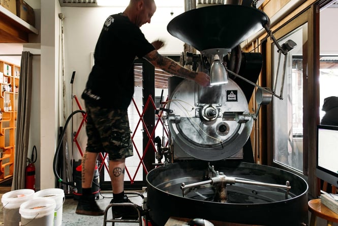 A man roasting coffee inside Hawthorne Coffee Roasters.