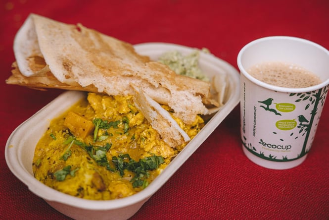 A close up of a curry and dosa on a red table.