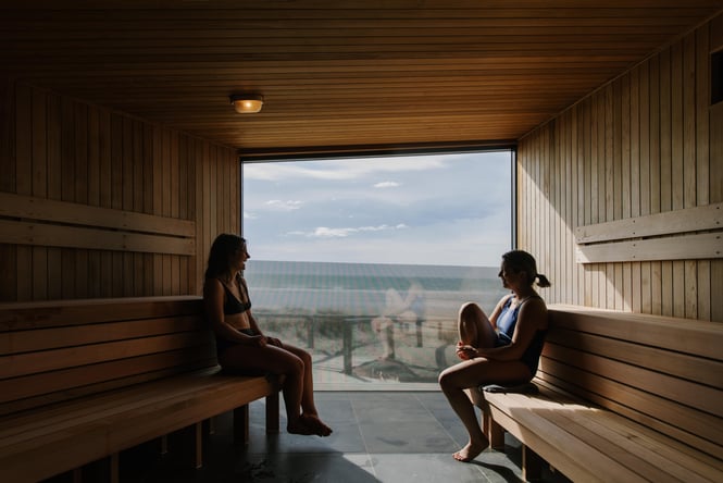 Two women inside a large sauna.