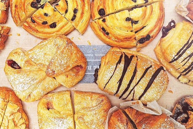 Fresh chocolate croissants, and danishes sprinkled with icing sugar.
