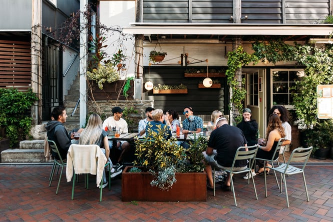 A large group of people dining outside a bar.