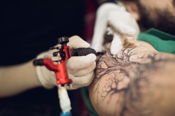 An arm being tattooed in black ink.