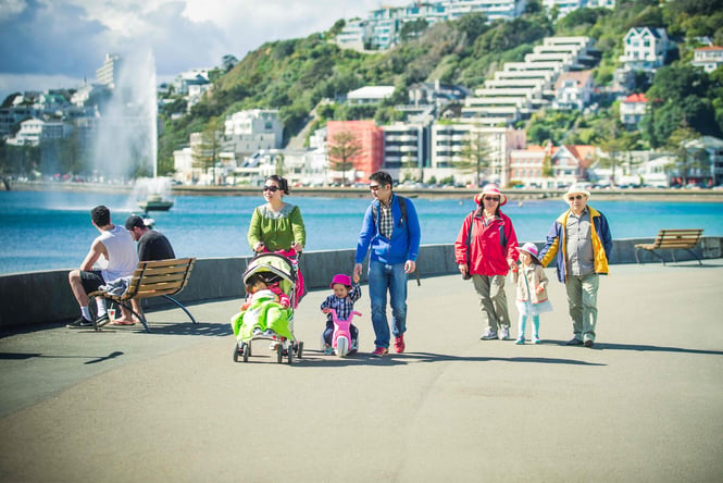 A three generational family walking along the water's edge in Wellington.