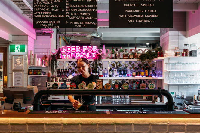 A woman pouring a beer behind a bar.