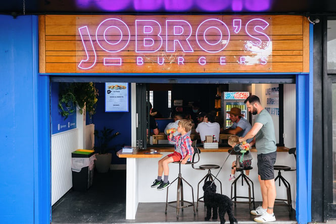 The exterior of Jo Bros Auckland with people sitting at the bench seating.