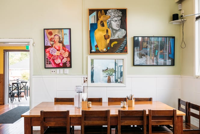 A large table underneath walls decorated with framed works of art.