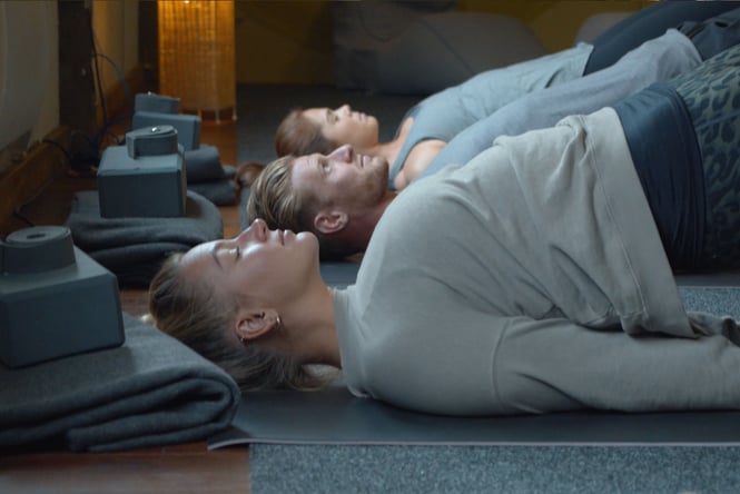Three people doing yoga with their eyes closed.