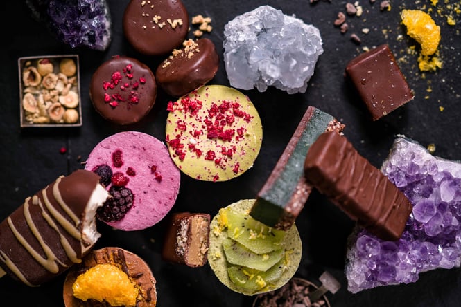 A colourful flatly of sweet treats from Good Roots on a black table.