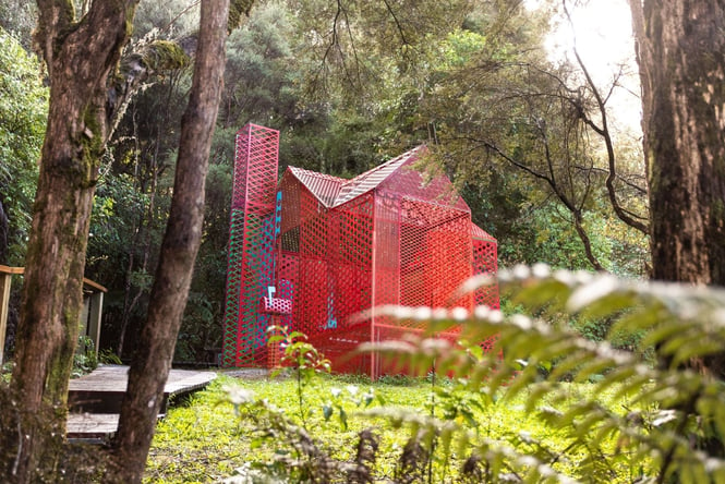 A red building-like sculpture amongst the trees.