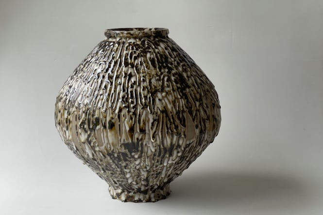 A close up of a dark coloured round vase.