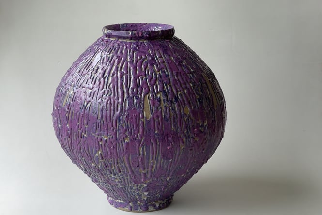 A close up of a dark purple round vase.