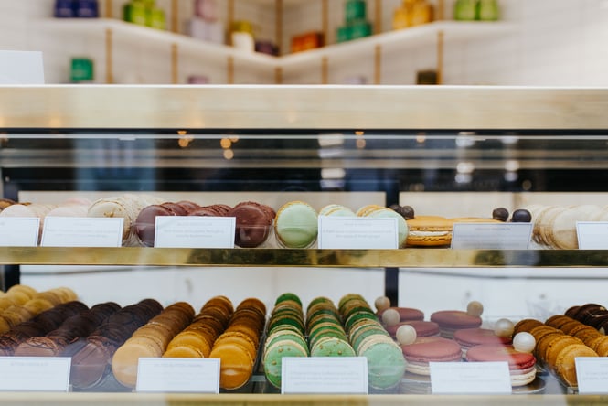 Rows of macarons on display behind a glass counter.