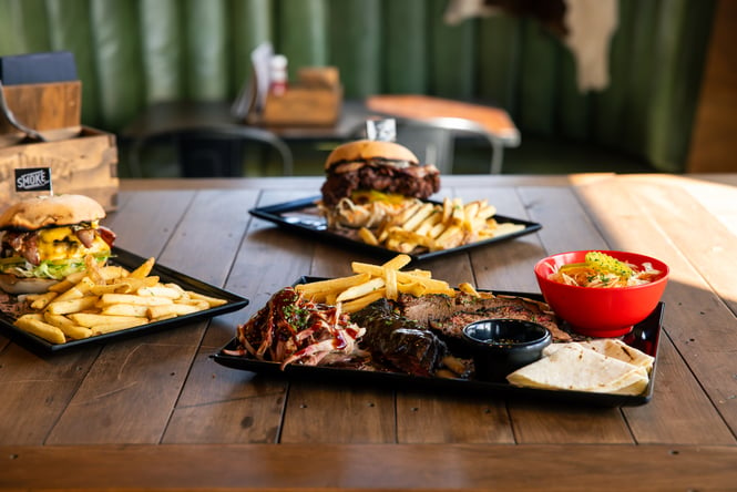 A close up of burgers and chips on a table.