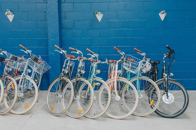 Colourful bikes lined up in front of a blue wall.