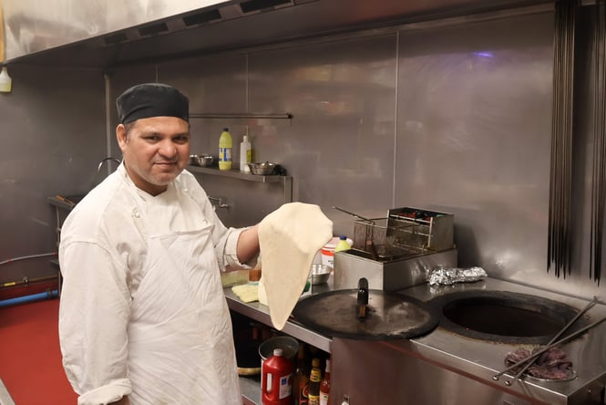 A chef holding dough and smiling to camera.