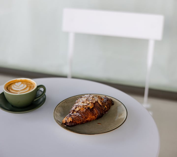 A coffee and croissant on a table.