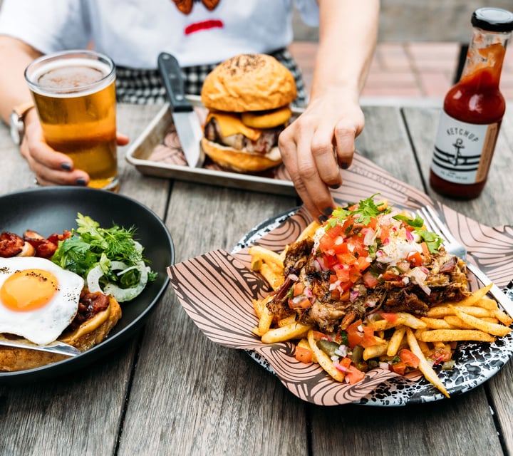 Loaded fries and other plates of food on an outdoor table.