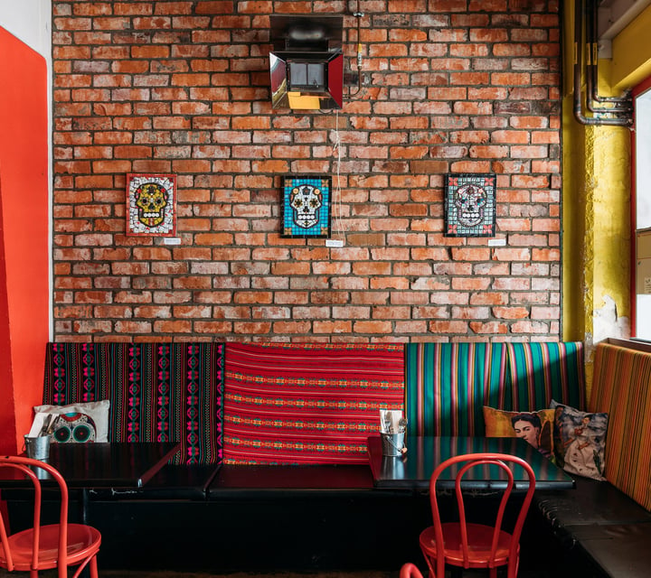 Interior of Mexican restaurant with exposed brick walls, Mexican skull mosaics and Day of the Dead decor