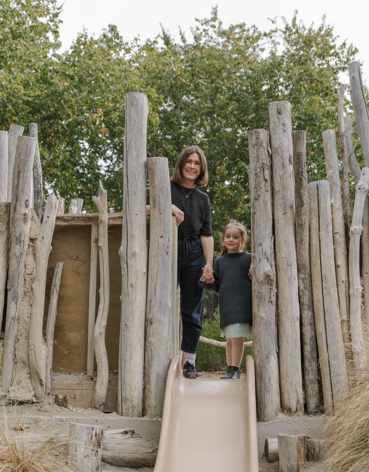 A woman and child standing amongst a log playground.