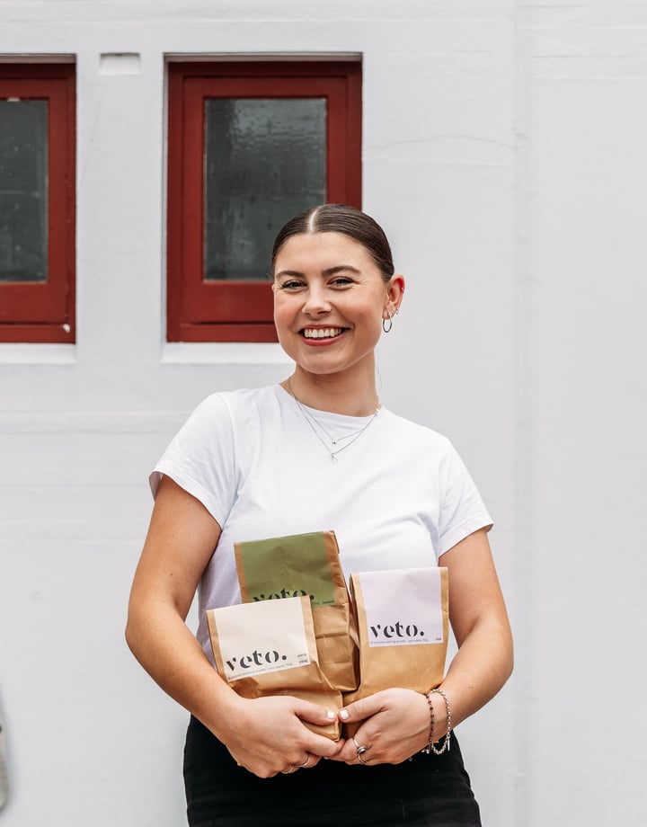 A woman holding paper bags and smiling to camera.
