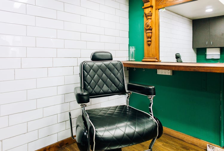 Black barber chair in front of salon mirror at Boar and Blade in Wellington