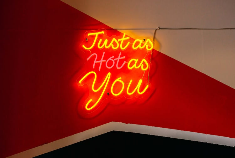 A fluorescent sign that says 'just as hot as you'.