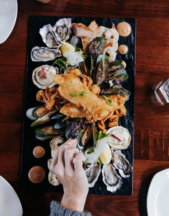 A hand reaching for a seafood platter at Oyster Cove in Southland.