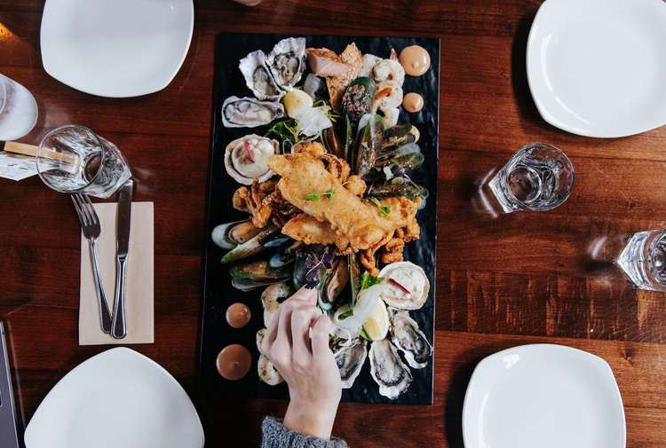 A hand reaching for a seafood platter at Oyster Cove in Southland.