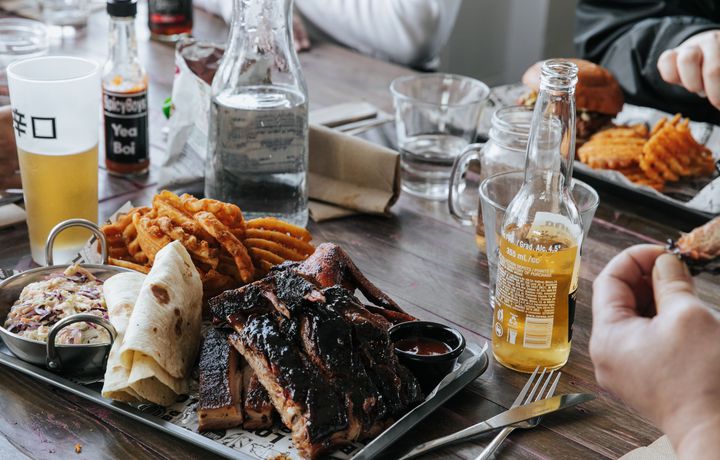 A plate of meat and chips on a table sittling alongside beers.