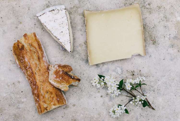 Cheese and bread on a table with flowers.