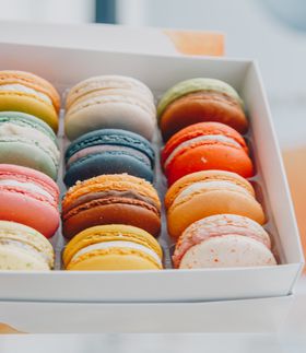 Brightly coloured macaroons in a white box.