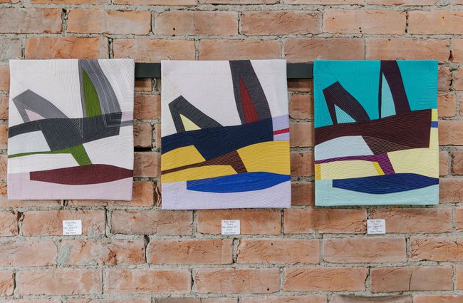 Three colourful paintings lined up on a brick wall at 77 Art + Living in Fairlie.