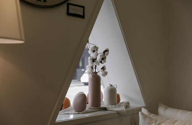 Triangle shaped window with vases on the sill.