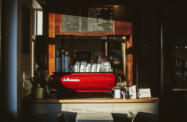 A barista working behind a bright red coffee machine.