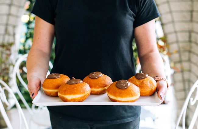 A baker holding a plate of doughnuts.