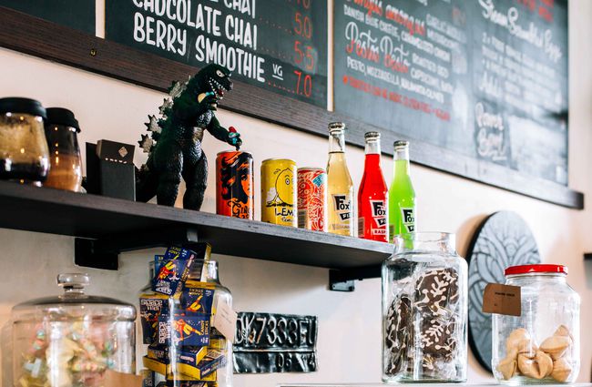 Drinks and dinosaur on display on a shelf.