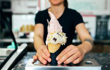 An employee serving a gelato waffle cone.