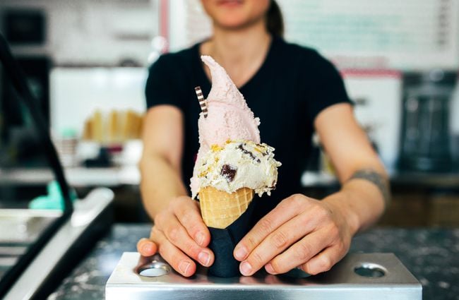 An employee serving a gelato waffle cone.