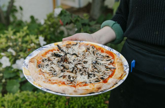 Person holding a pizza from Bloom Cafe, Motueka.