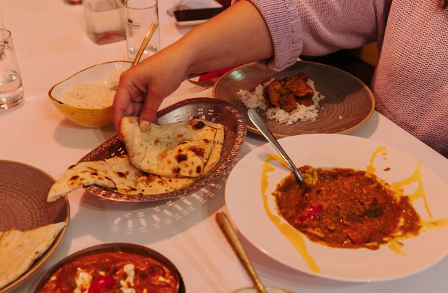 Woman reaching for naan bread.