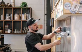 Side view of a man pouring a beer from taps at Brew Academy in Christchurch.