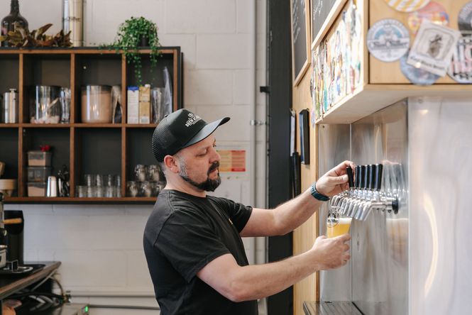 Side view of a man pouring a beer from taps at Brew Academy in Christchurch.
