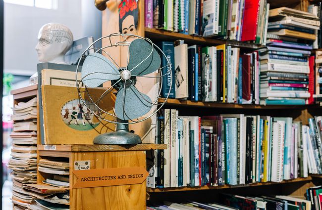 A blue vintage fan sitting next to books.