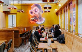 Yellow wall with woman eating a burger mural.