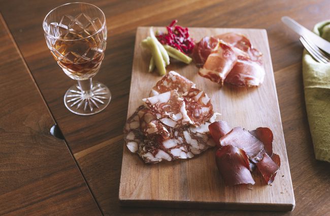 Cured meat platter on table with wine.