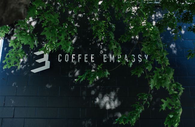 Outdoor Coffee Embassy signage on a brick wall.