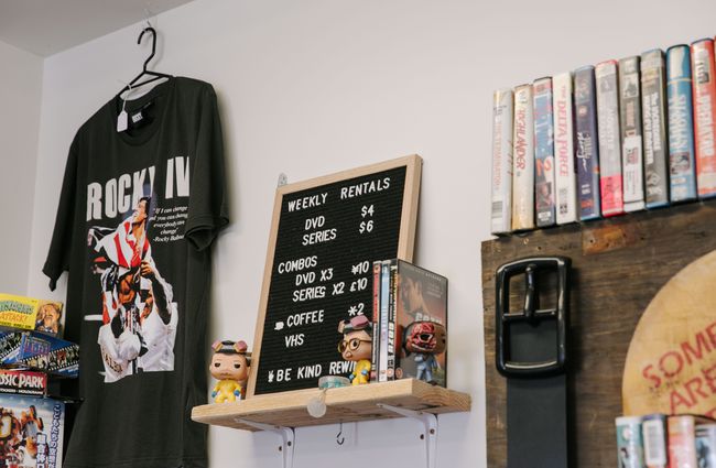 Price board and t-shirt hanging on the wall at Dead Video in Lyttelton.