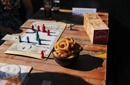Close up of a bowl of onion rings next to board game at Dice and Slice in Christchurch.