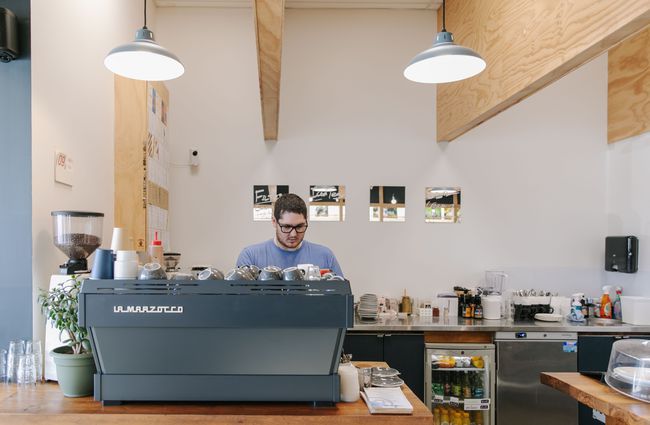 Man making coffee behind blue coffee machine at Dispense Espresso in Christchurch.