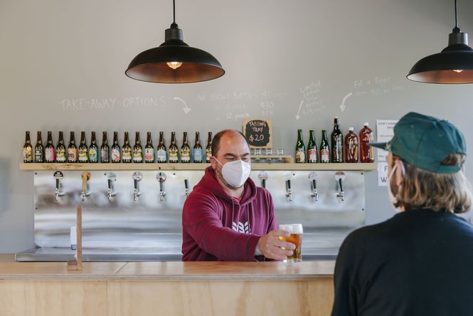 Man giving a customer a pint of Emporium Brewing beer.